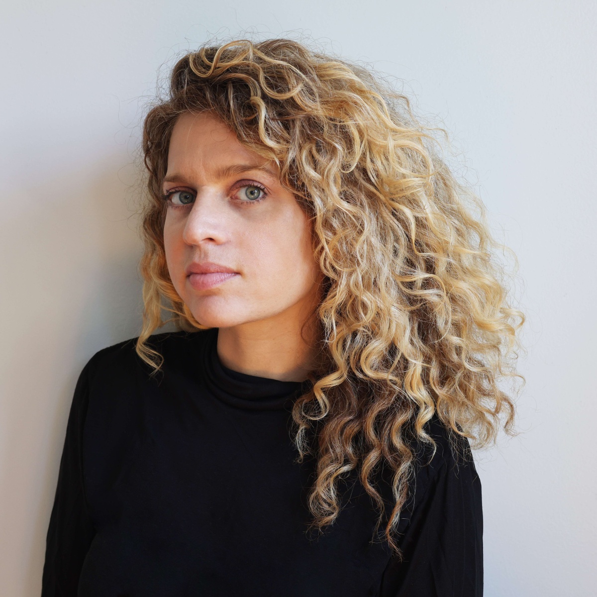 headshot of artist miriam simun, a light-skinned femme with curly blonde hair in black sweater